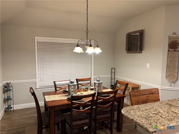 a view of a dining room and livingroom with furniture wooden floor a rug and a chandelier