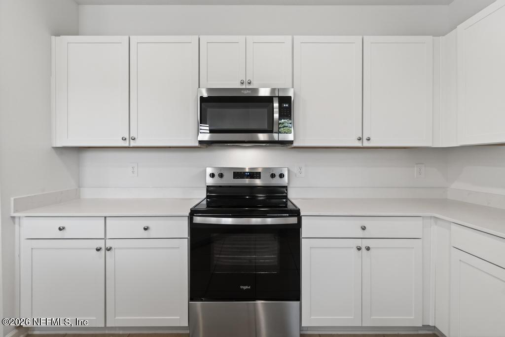 45 Seaport Breeze Road St. Augustine, FL 32095 - Photo 17 of 88 a kitchen with white cabinets and black appliances