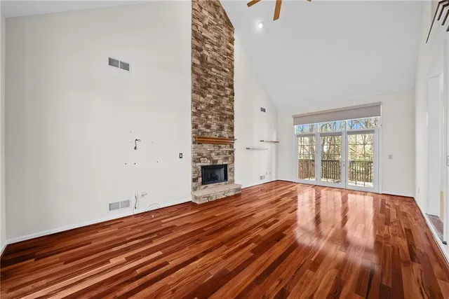 a view of an empty room with wooden floor and windows
