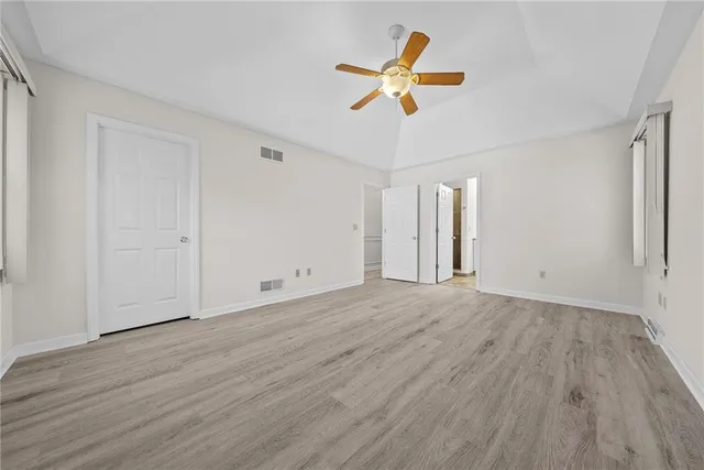 an empty room with wooden floor and ceiling fan