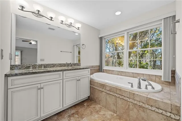a bathroom with a granite countertop tub a sink and a window