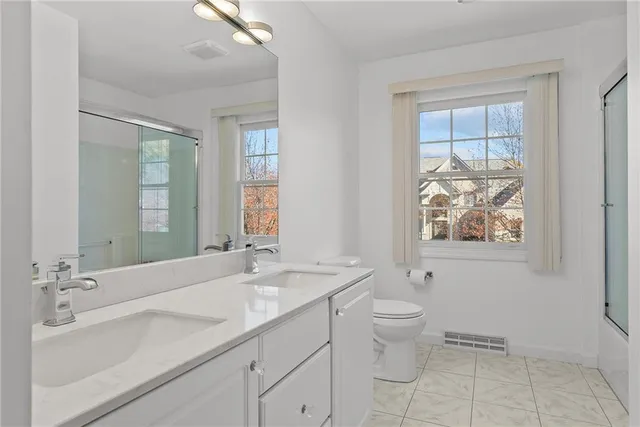 a bathroom with a double vanity sink toilet and a tub