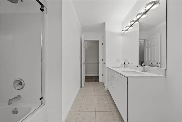 a bathroom with a double vanity sink a mirror and a bathtub