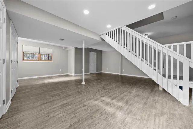 a view of an empty room with stairs and a window