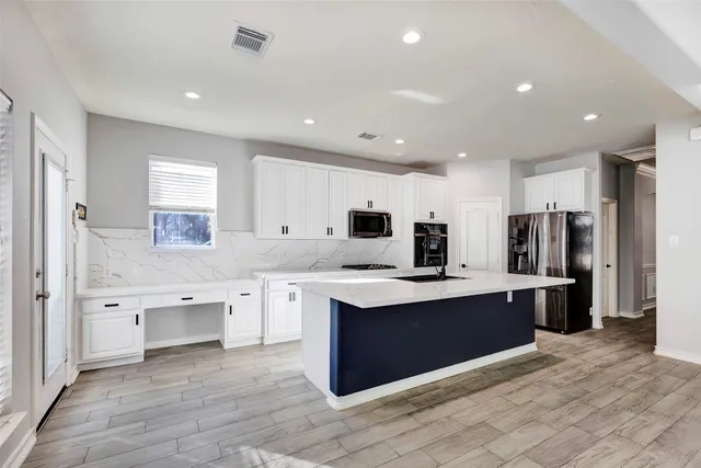 a large kitchen with stainless steel appliances kitchen island granite countertop a large stove a sink dishwasher and a refrigerator with wooden floor