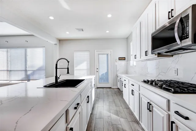 a kitchen with stainless steel appliances kitchen island a stove a sink and a microwave