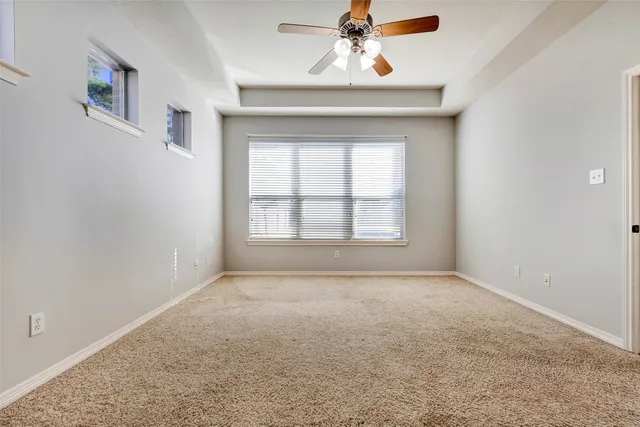 an empty room with windows and chandelier fan