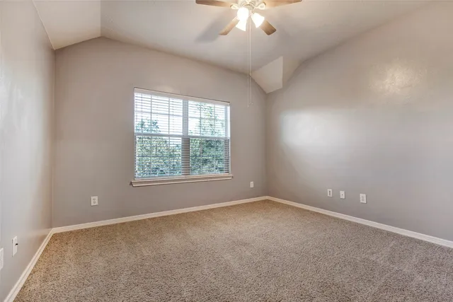 an empty room with a chandelier fan and window