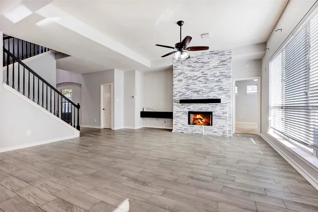 a view of an empty room with wooden floor fireplace and a window