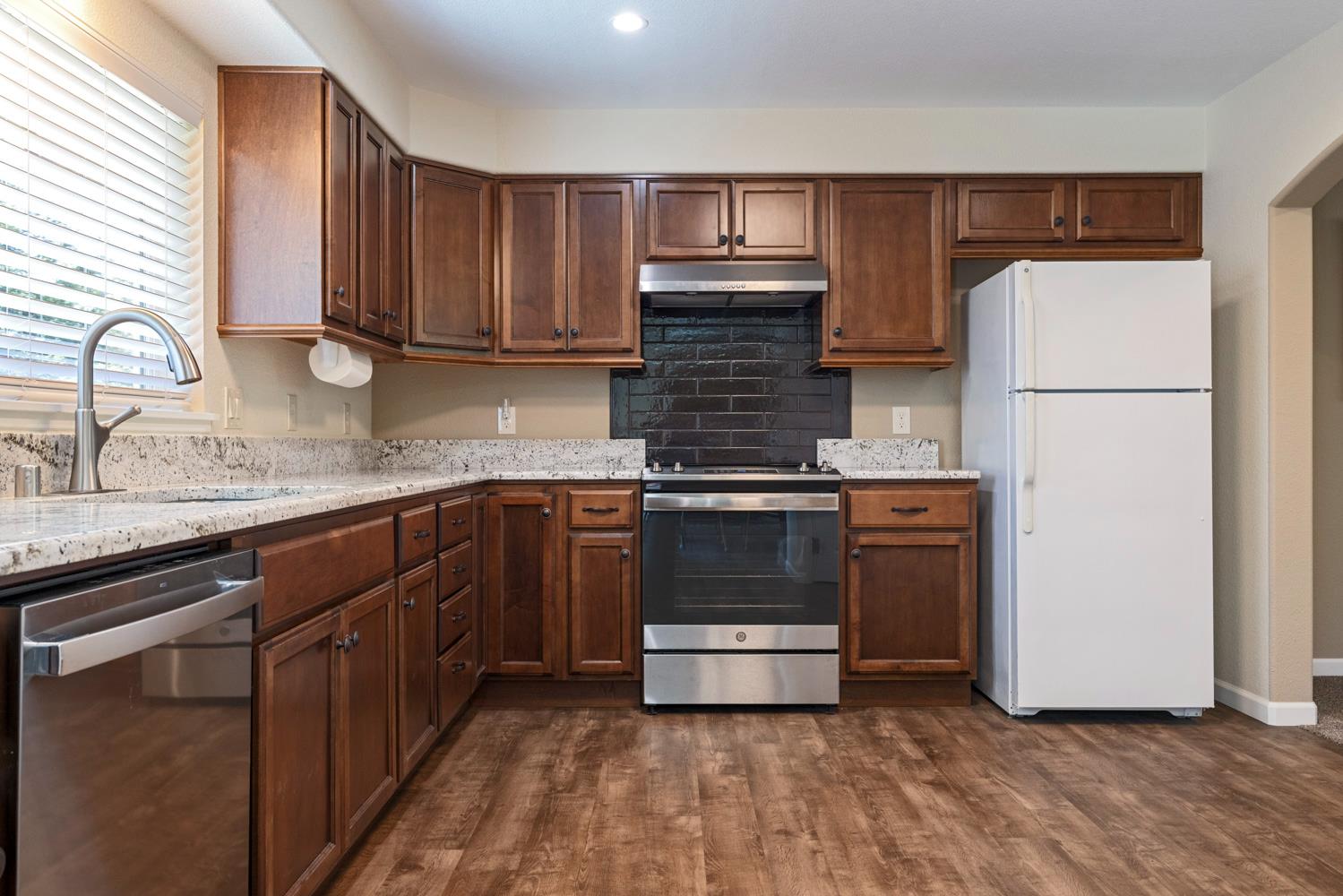 1255 Root Road Modesto, CA 95357 - Photo 22 of 52 a kitchen with kitchen island granite countertop wooden cabinets and white appliances