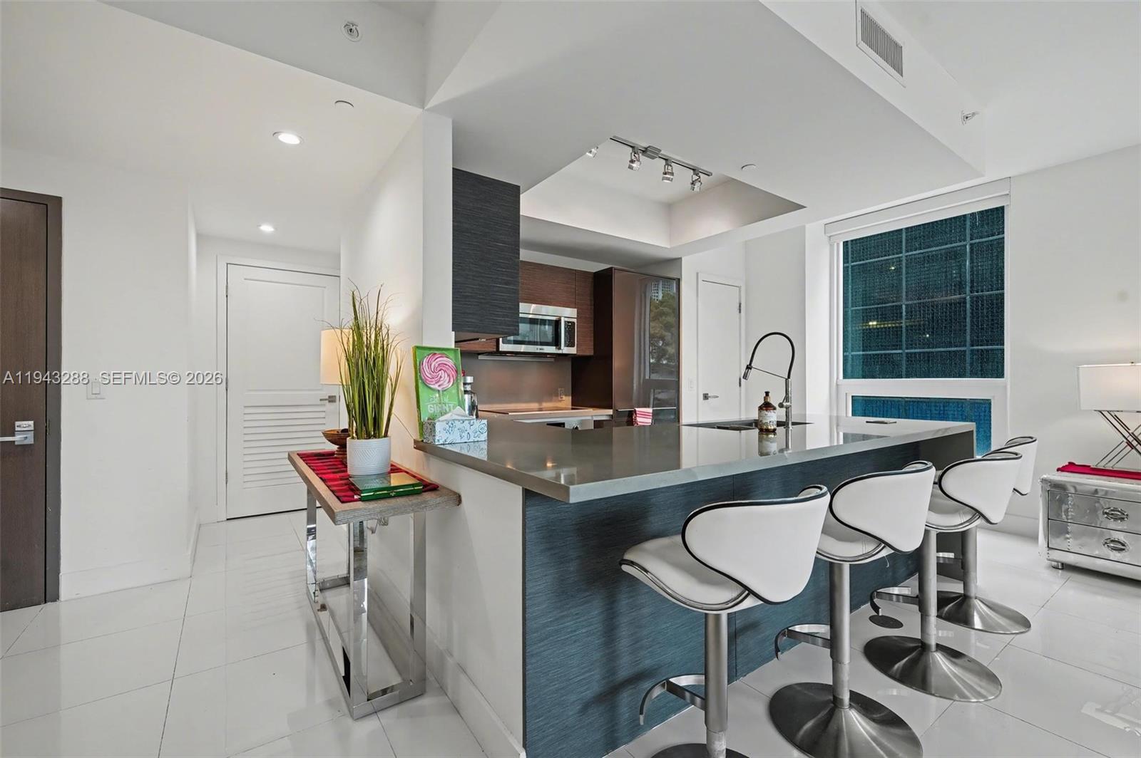 1080 Brickell Avenue, Unit 209 Miami, FL 33131 - Photo 10 of 37 a kitchen with kitchen island granite countertop a sink and a refrigerator