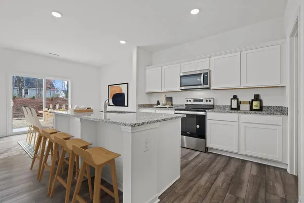 a kitchen with stainless steel appliances granite countertop white cabinets a sink dishwasher a stove and a refrigerator with wooden floor