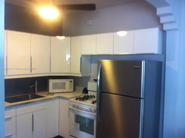 a kitchen with a refrigerator sink and cabinets
