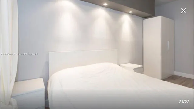 a large white bed in a room next to a window