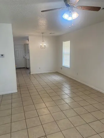 an empty room with chandelier fan and windows