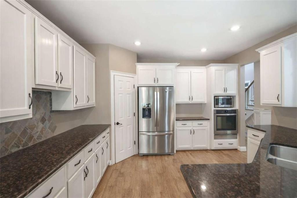 1660 A Maple Ridge Drive Loganville, GA 30052 - Photo 25 of 51 a kitchen with granite countertop a refrigerator and a stove top oven