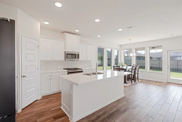 a kitchen with stainless steel appliances granite countertop a refrigerator a stove and a wooden floors