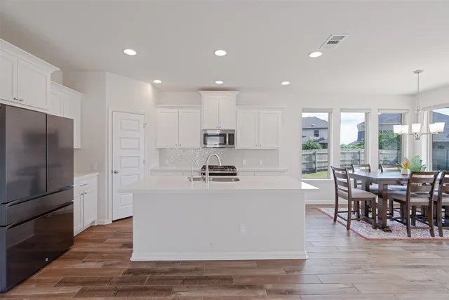 a living room with stainless steel appliances granite countertop furniture wooden floor and a kitchen view