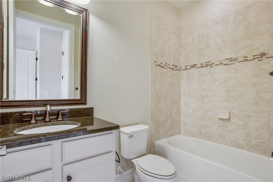 10828 Rutherford Road Fort Myers, FL 33913 - Photo 17 of 31 a bathroom with a granite countertop sink toilet vanity mirror bathtub and shower
