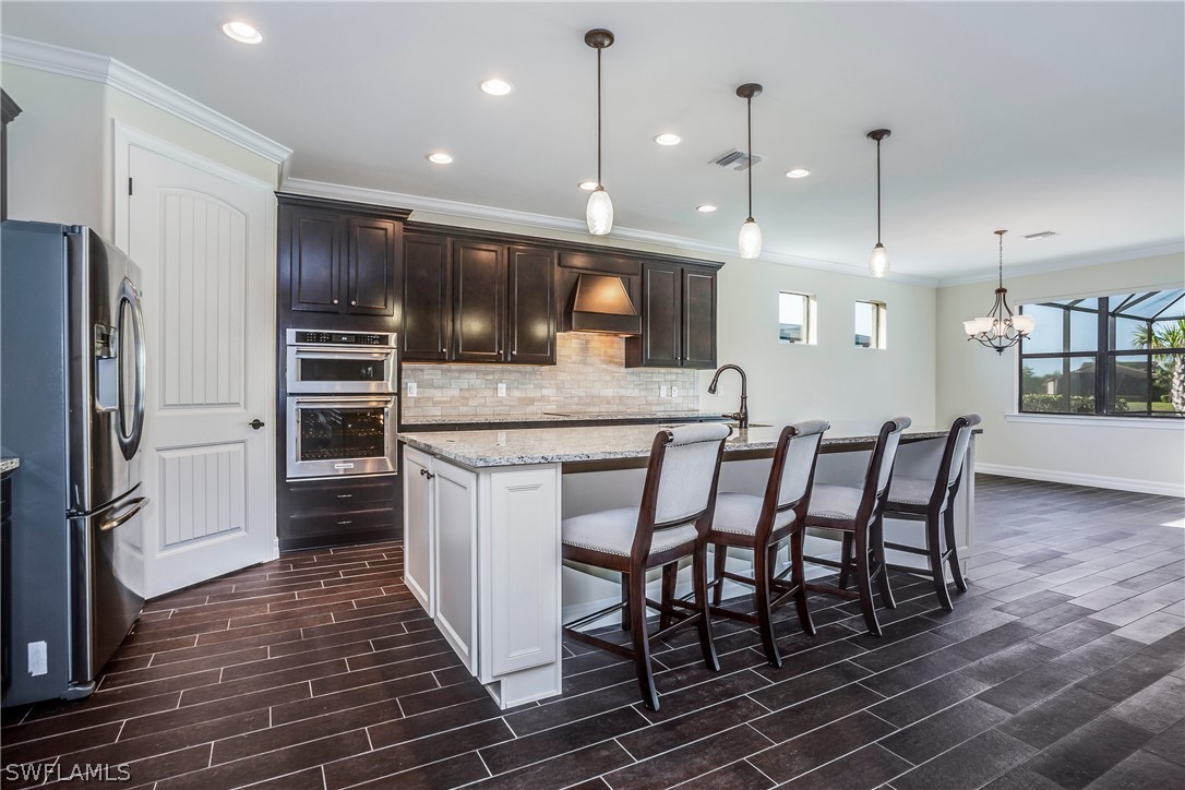 10828 Rutherford Road Fort Myers, FL 33913 - Photo 6 of 31 a kitchen with stainless steel appliances granite countertop a kitchen island a stove a refrigerator a oven a sink with a dining table and chairs