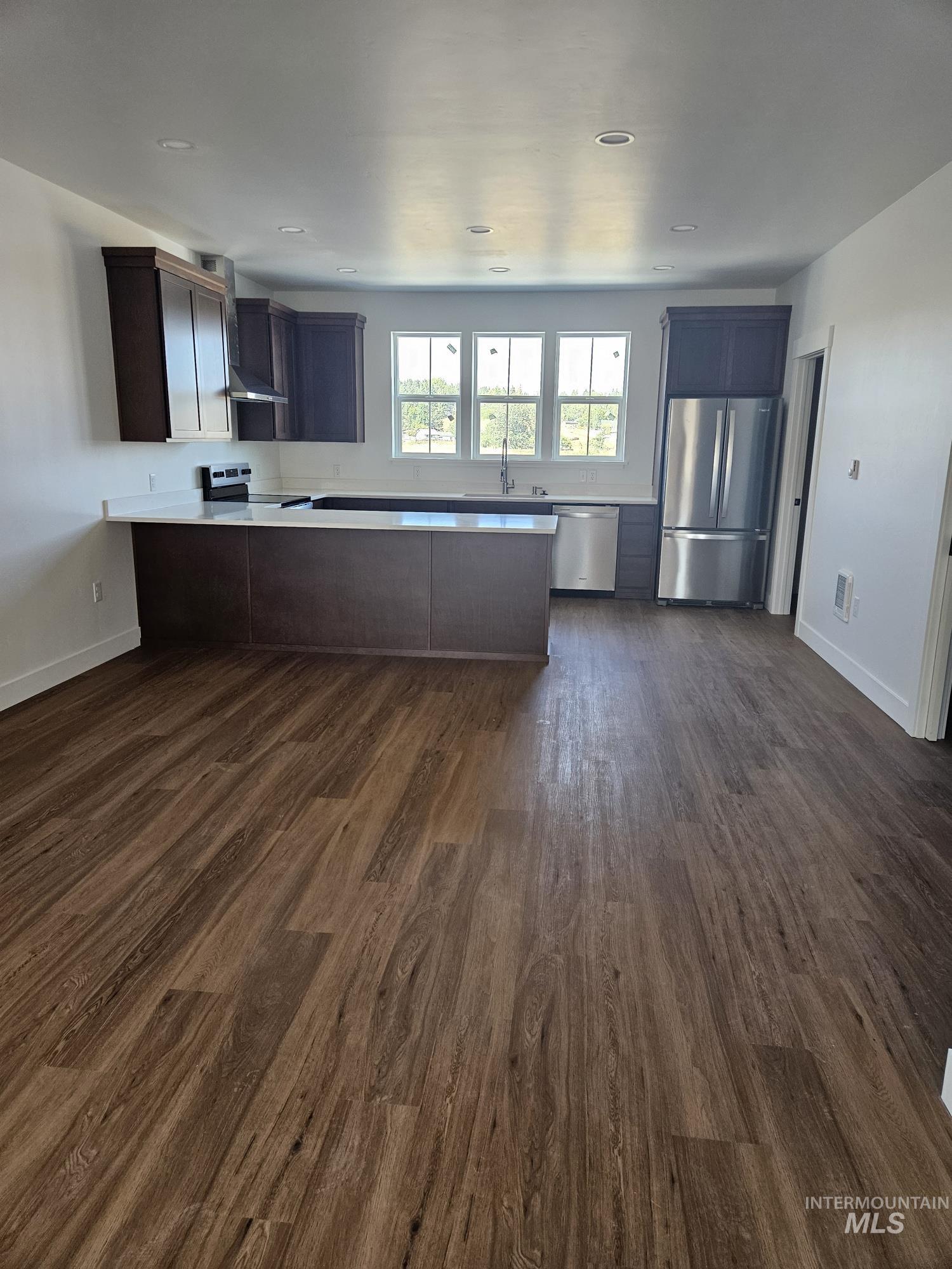 1198 Edington Moscow, ID 83843 - Photo 3 of 11 Kitchen featuring light countertops, stainless steel appliances, dark wood finish cabinets, a peninsula, and dark wood-style floors