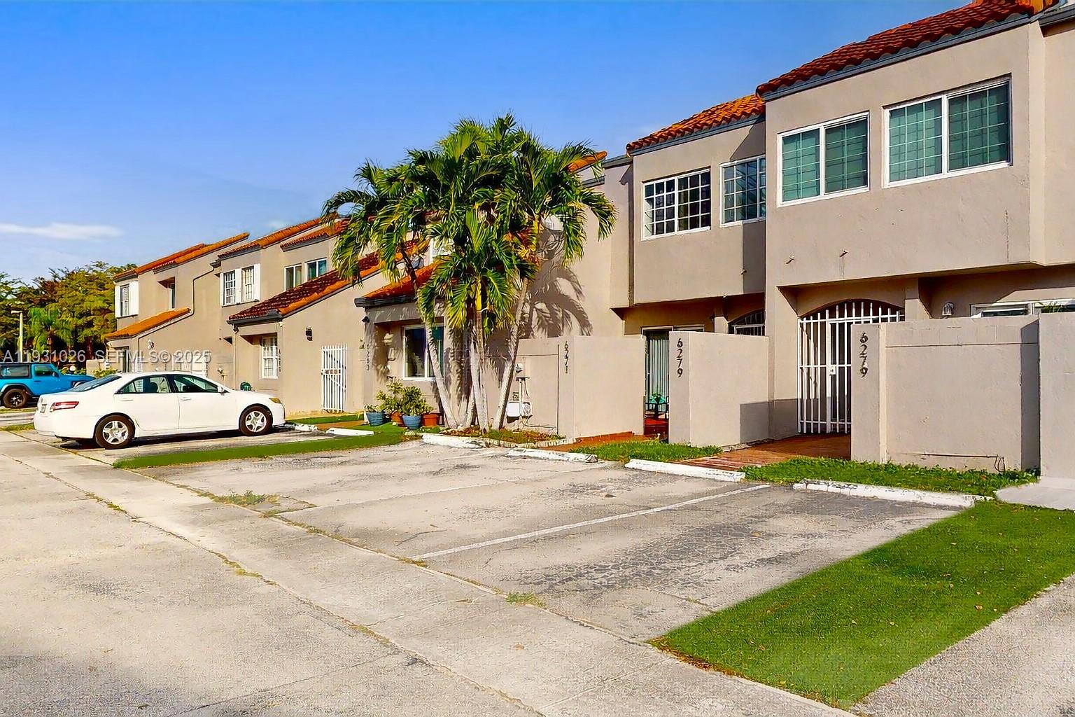 6279 Southwest 128th Court Miami, FL 33183 - Photo 2 of 32 a view of a white house with a yard and table and chairs under an umbrella