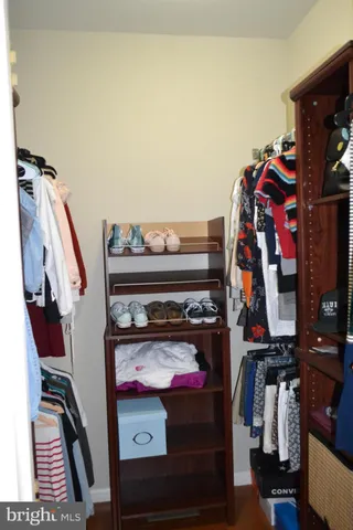 a view of walk in closet with clothes and shoes