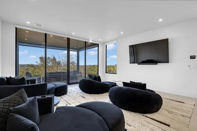 a living room with furniture a flat screen tv and a floor to ceiling window