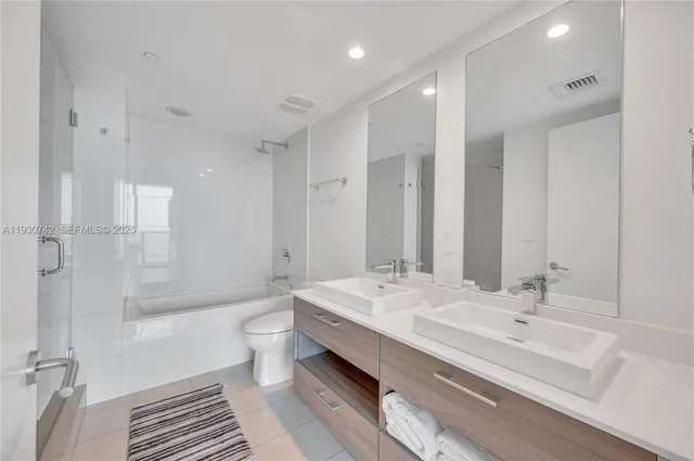 a bathroom with a double vanity sink toilet mirror and bathtub