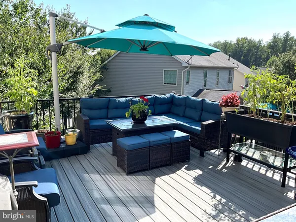 a view of a patio with couches table and chairs under an umbrella with wooden floor