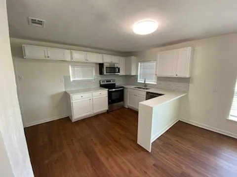a kitchen with a white cabinets a sink a window and wooden floor