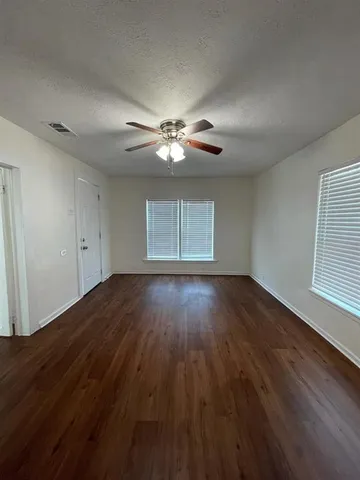 a view of empty room with wooden floor and fan