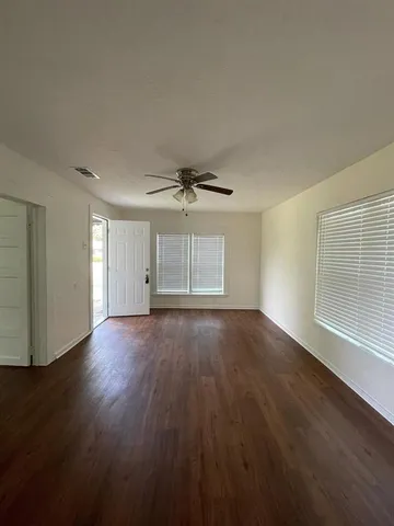 a view of empty room with wooden floor and fan