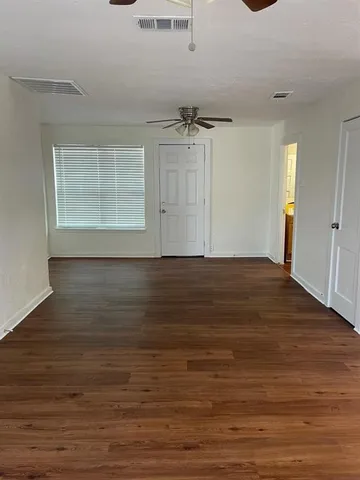 an empty room with wooden floor cabinet and windows