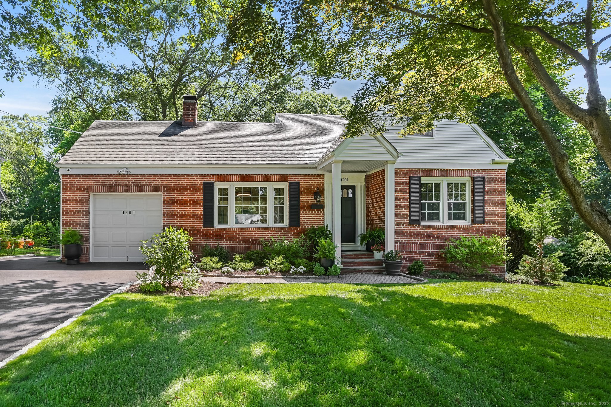 a front view of a house with a yard and large trees
