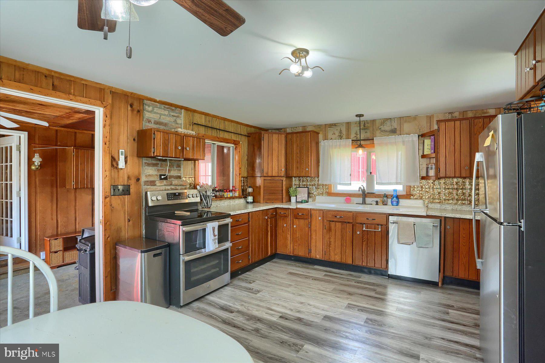 1560 Rhine Hollow Road East Waterford, PA 17021 - Photo 77 of 113 a kitchen with stainless steel appliances granite countertop a refrigerator a sink dishwasher a stove and white countertops with wooden floor