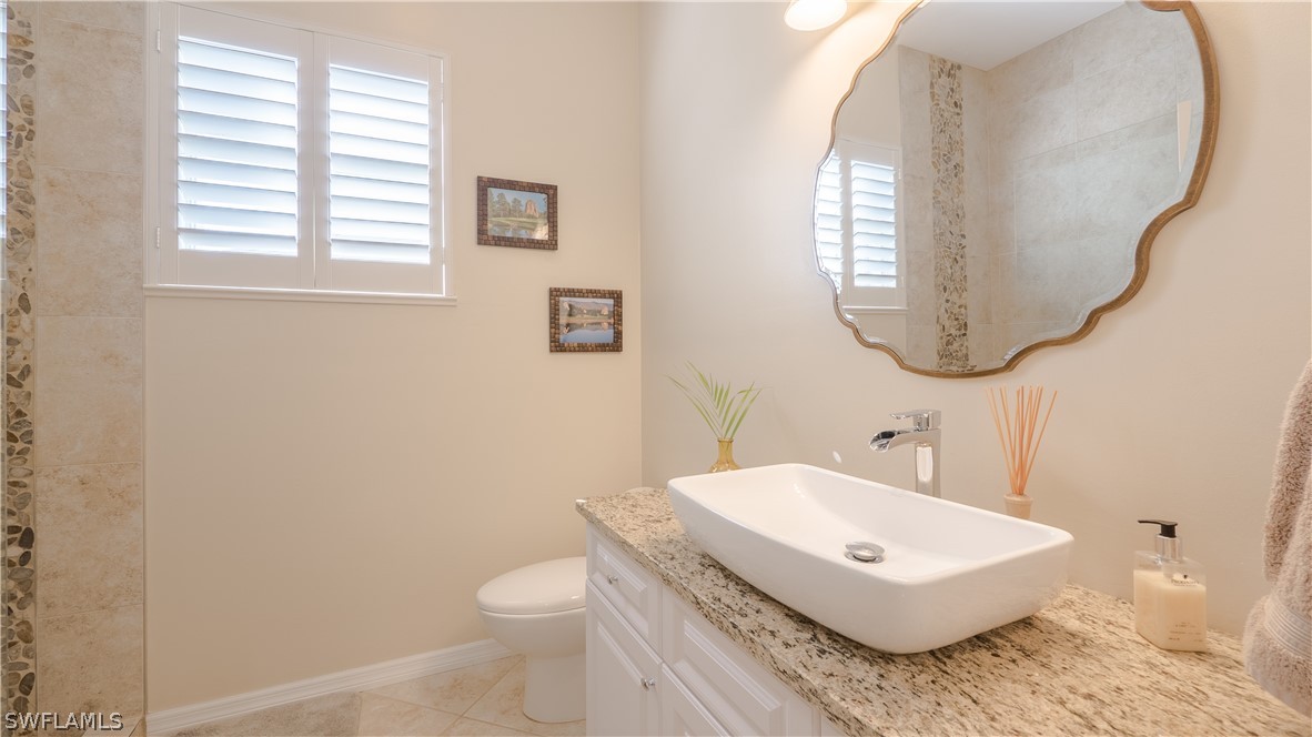 8734 Brittania Drive Fort Myers, FL 33912 - Photo 21 of 34 a bathroom with a granite countertop toilet a sink and a mirror