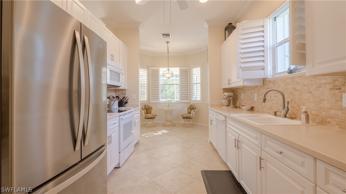 8734 Brittania Drive Fort Myers, FL 33912 - Photo 6 of 34 a large white kitchen with a sink a refrigerator and cabinets