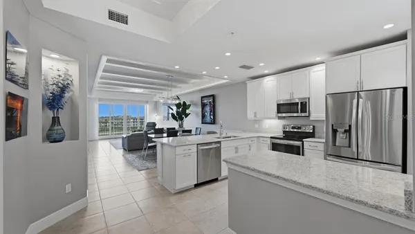 a kitchen with stainless steel appliances granite countertop a refrigerator oven a sink dishwasher and white cabinets with wooden floor