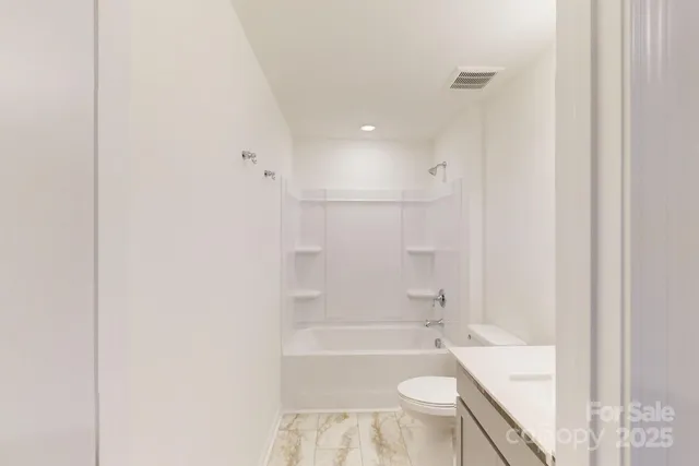 a bathroom with a granite countertop bathtub shower sink vanity and toilet