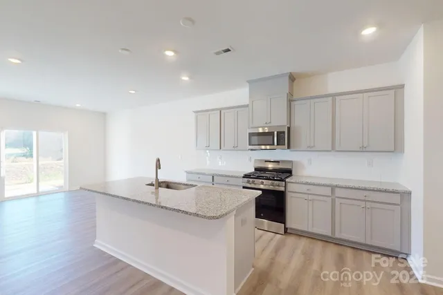 a kitchen with stainless steel appliances granite countertop a sink stove and refrigerator