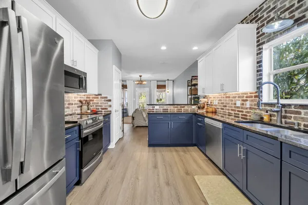 a kitchen with stainless steel appliances granite countertop a refrigerator a stove and a sink