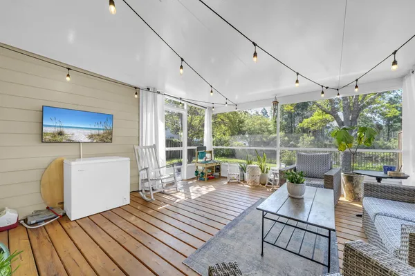 a living room with furniture a rug floor to ceiling window and wooden floor