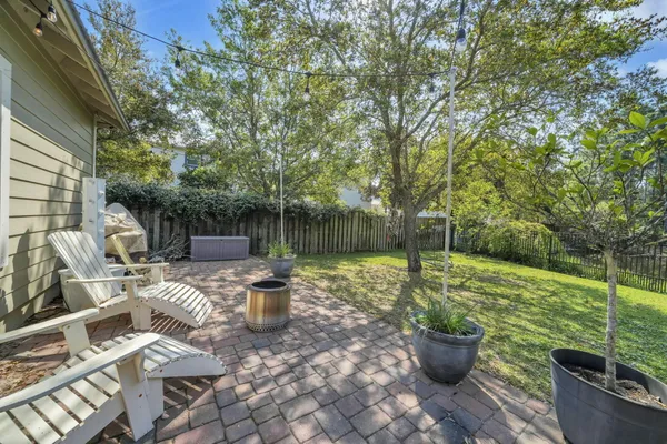 a view of a backyard with table and chairs potted plants and tree