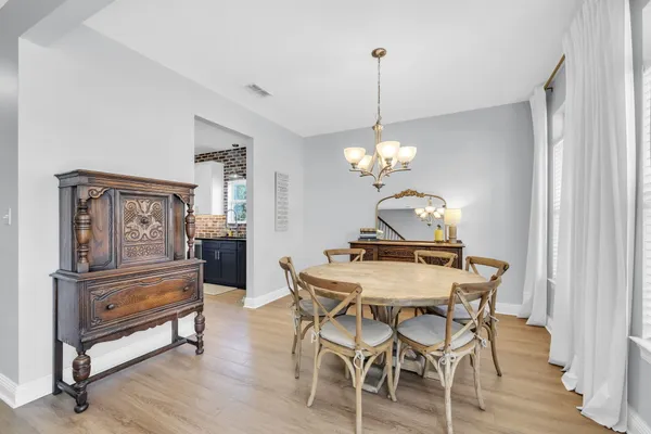 a dining room with wooden floor a chandelier a wooden table and chairs