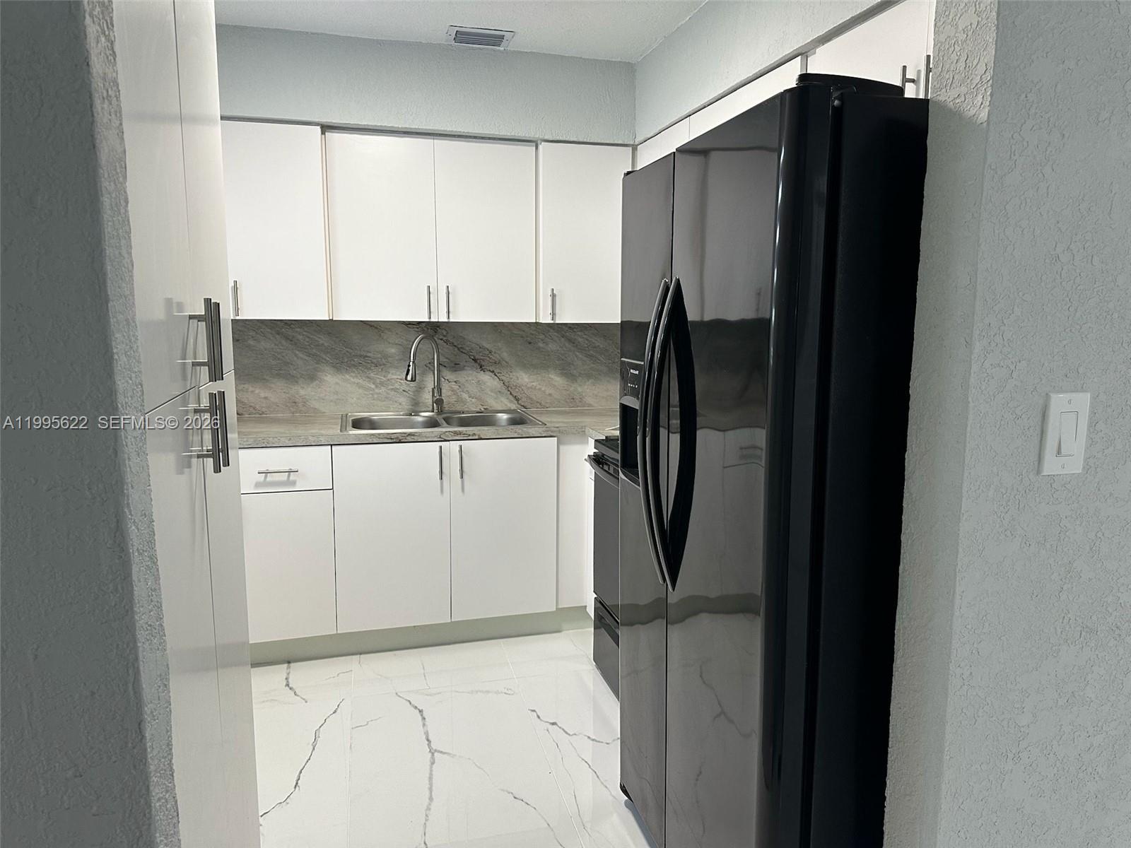 10745 Southwest 222nd Street, Unit 10745 Miami, FL 33170 - Photo 7 of 26 a view of a refrigerator in kitchen and white cabinets