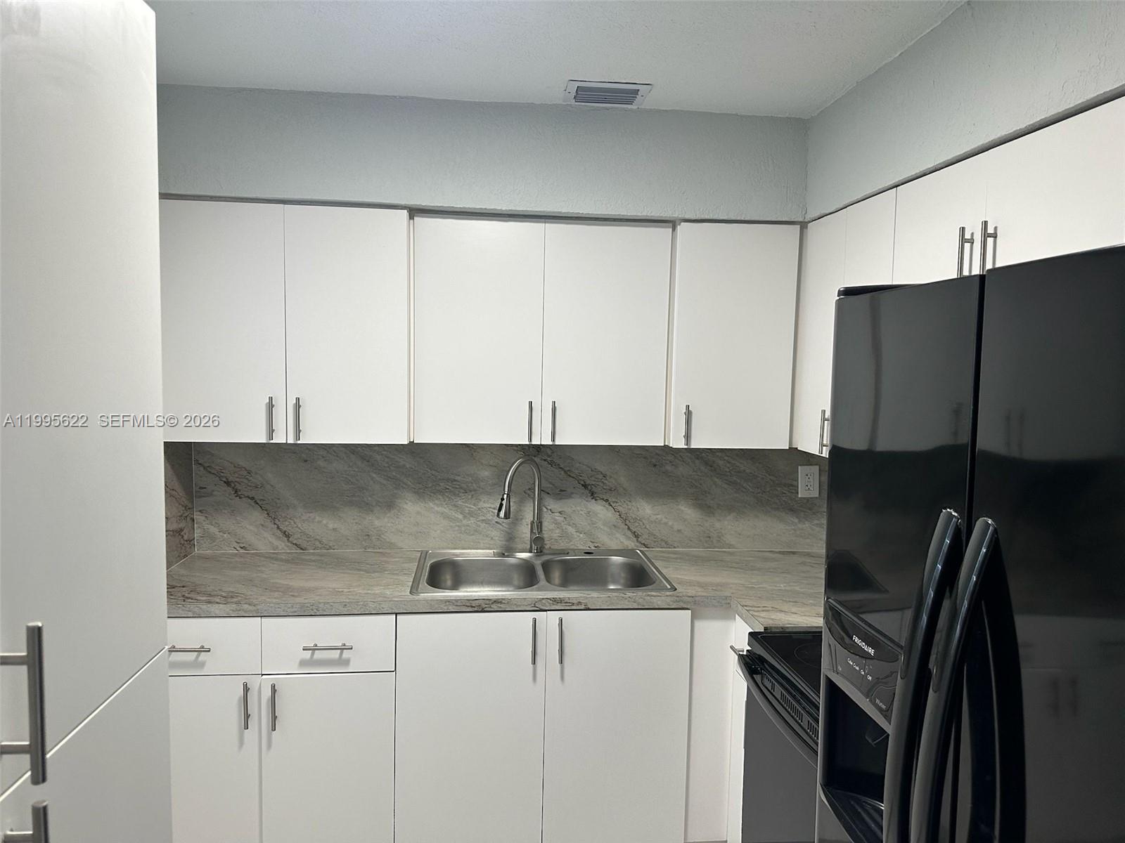10745 Southwest 222nd Street, Unit 10745 Miami, FL 33170 - Photo 9 of 26 a kitchen with granite countertop a cabinets and a stove top oven