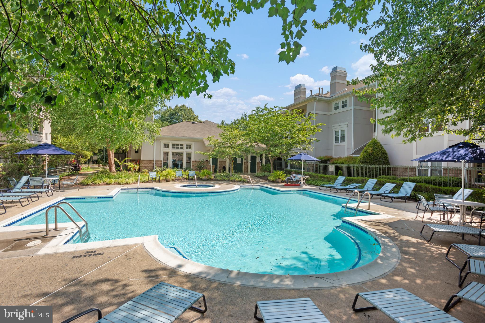 12004 Taliesin Place, Unit 32 Reston, VA 20190 - Photo 23 of 26 a view of a swimming pool with lawn chairs under an umbrella