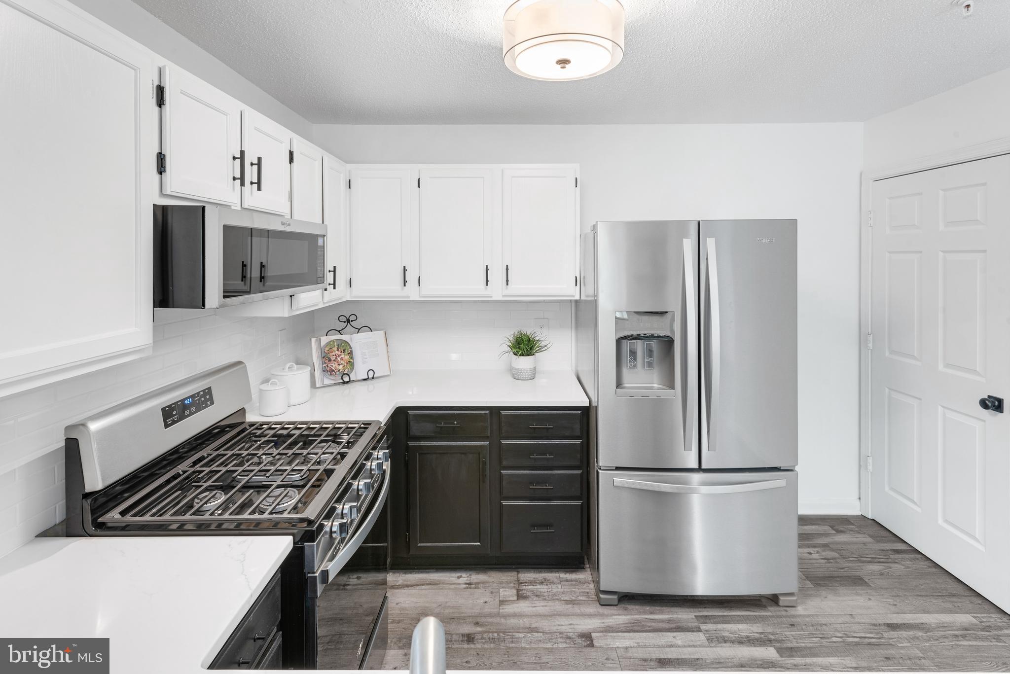 12004 Taliesin Place, Unit 32 Reston, VA 20190 - Photo 9 of 26 a kitchen with stainless steel appliances granite countertop a refrigerator stove a sink and white cabinets