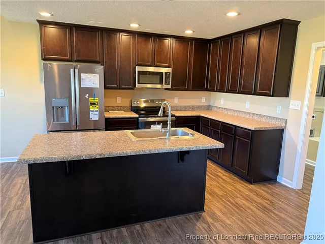 a kitchen with stainless steel appliances wooden cabinets a sink and a refrigerator